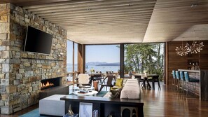 A modern living room with a stone fireplace, a flat-screen TV, and a view of the sea. - Unparalleled Luxury and Family Adventure at The Ritz-Carlton Club- 4 Bd. Res (Truckee)