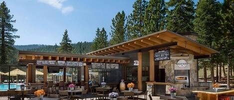 An outdoor seating area with tables and chairs, a pool, and a stone building labeled 'BACKYARD'.
