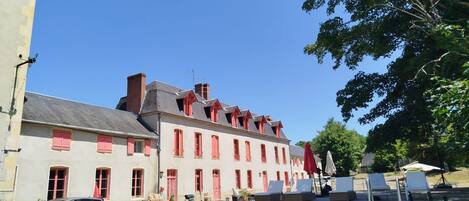 A building with a swimming pool, red shutters, and a clear blue sky.