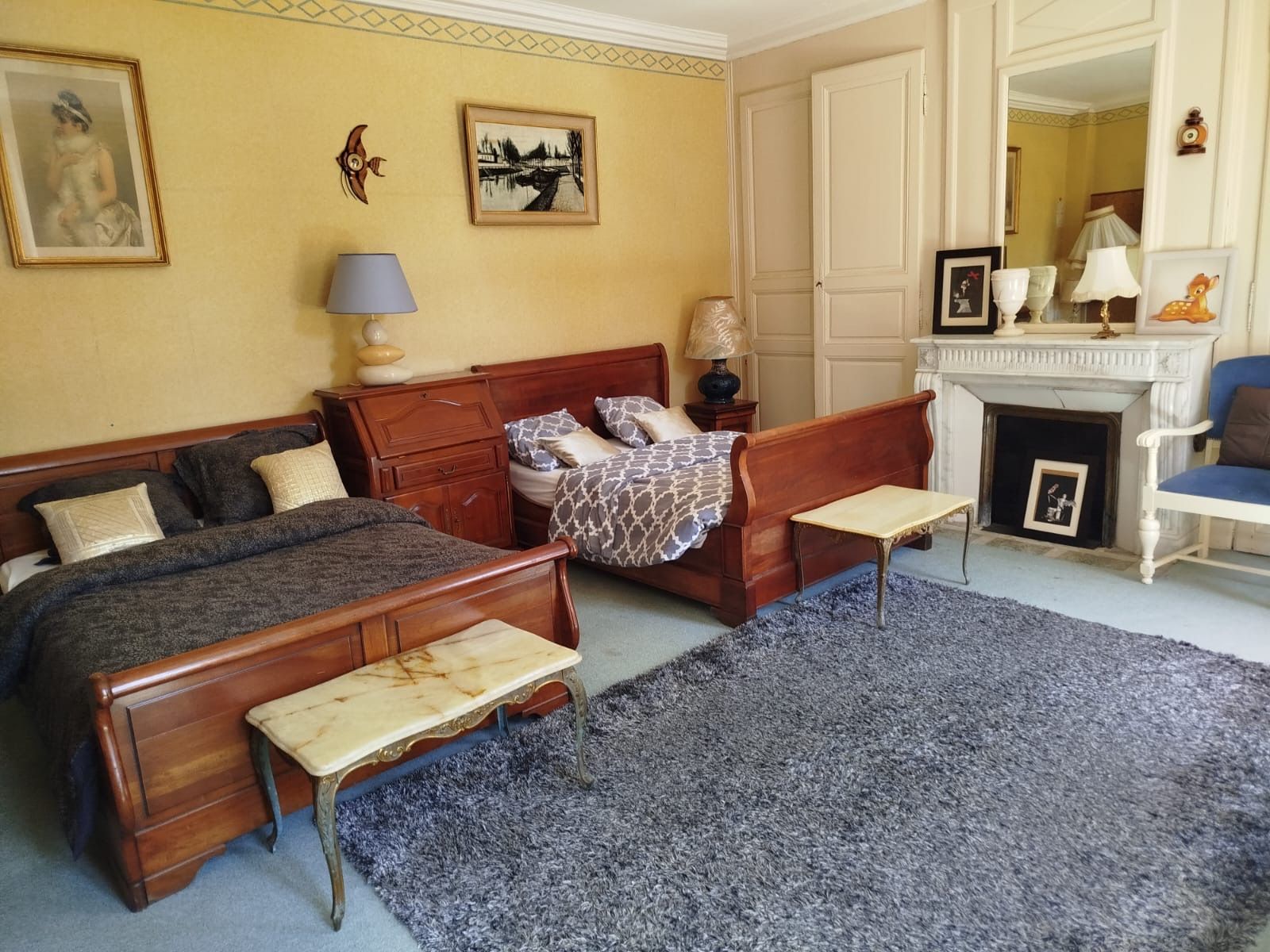 Ein Schlafzimmer mit zwei Holzbetten, einem kleinen Tisch, einem Kamin und einem Sessel.