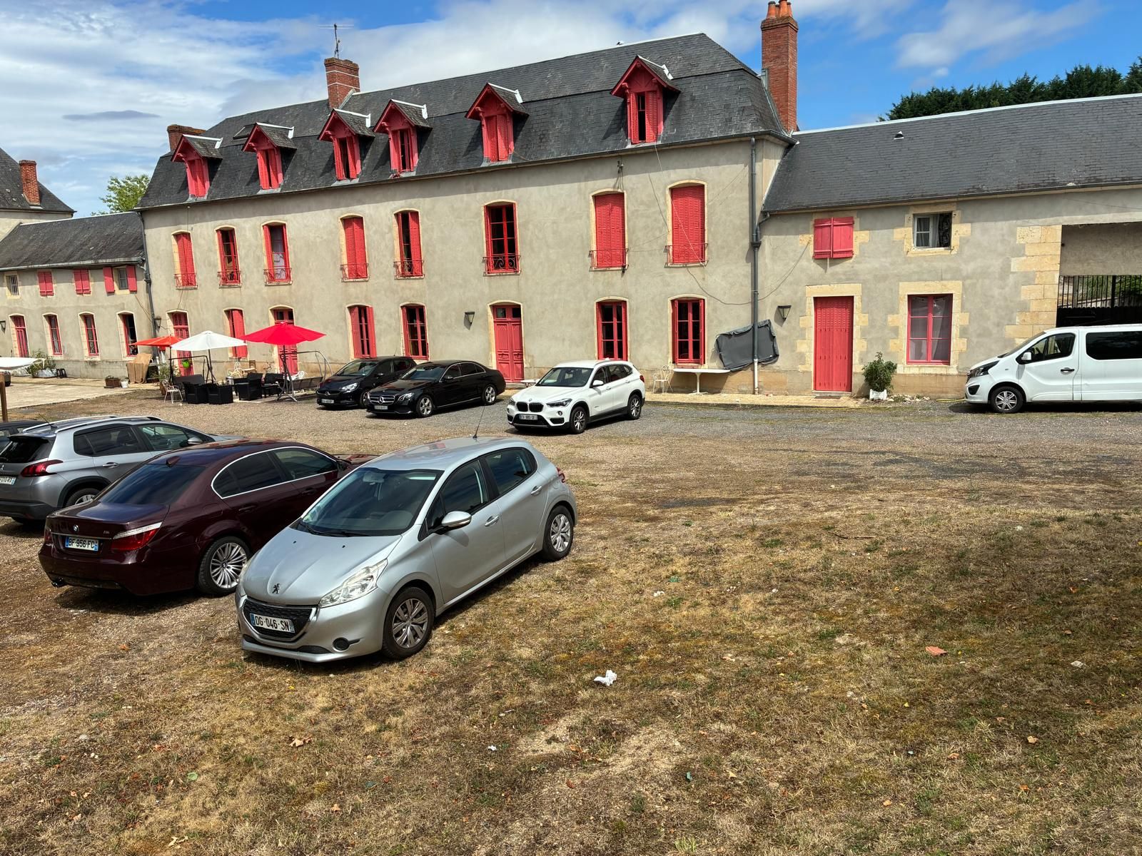 A building with multiple windows and a parking area with several cars.