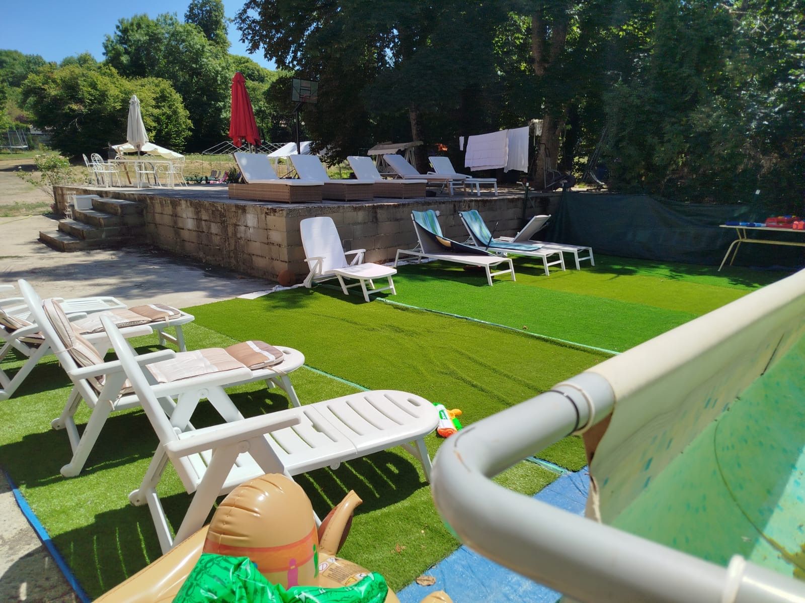 Un espace piscine avec des chaises longues et une petite table.