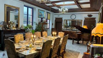 Ein Esszimmer mit großem Esstisch, einem Klavier und einer Kristallleuchter.