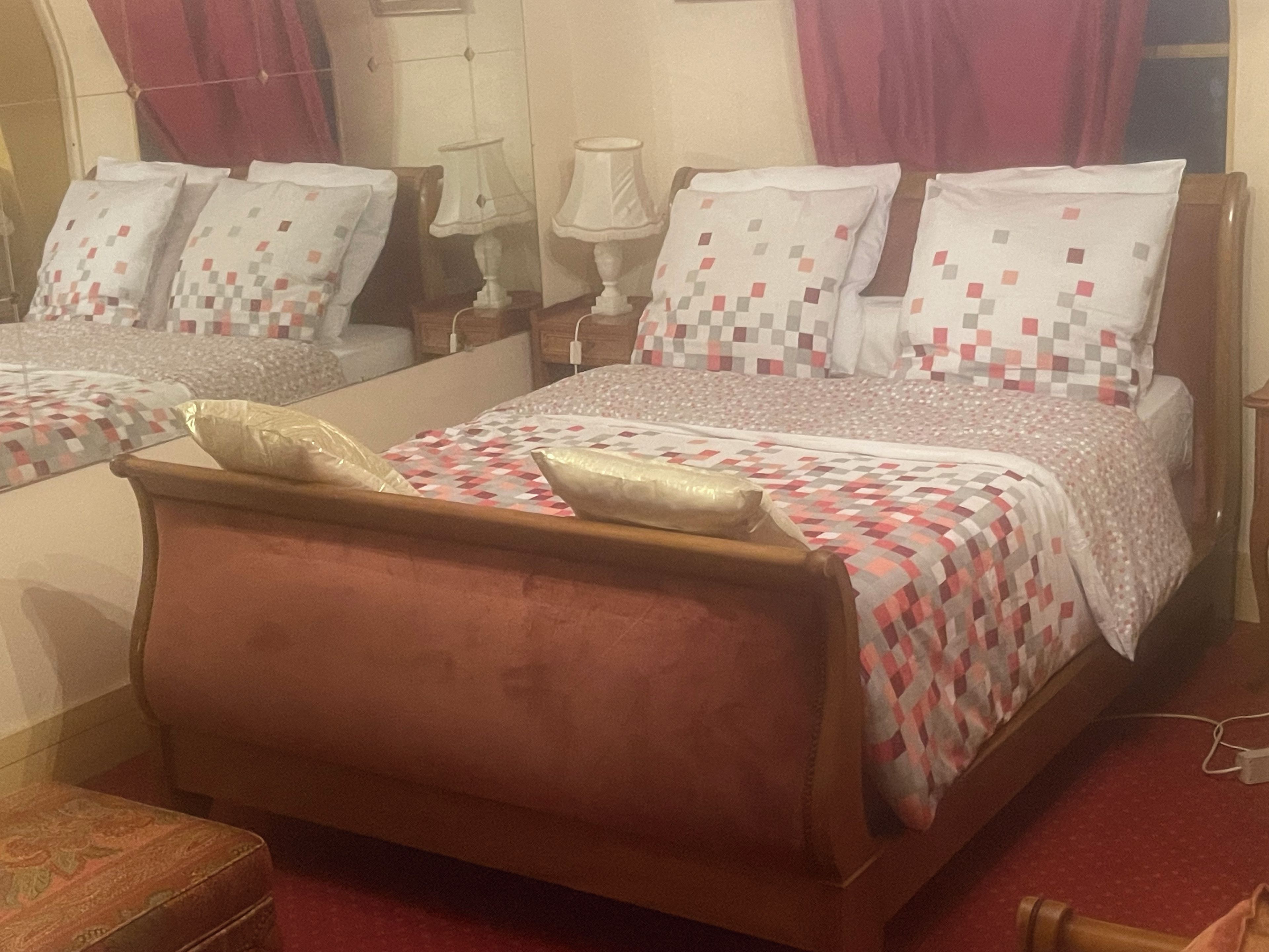 Une chambre à coucher avec un grand lit, une tête de lit en bois et une table de chevet avec une lampe.