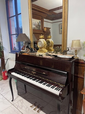 A grand piano in a room with a large mirror, a window with blue trim, and decorative items including a lamp and figurines. - 18TH-CENTURY CLAIREFONTAINE GARCHIZY CASTLE (Garchizy)