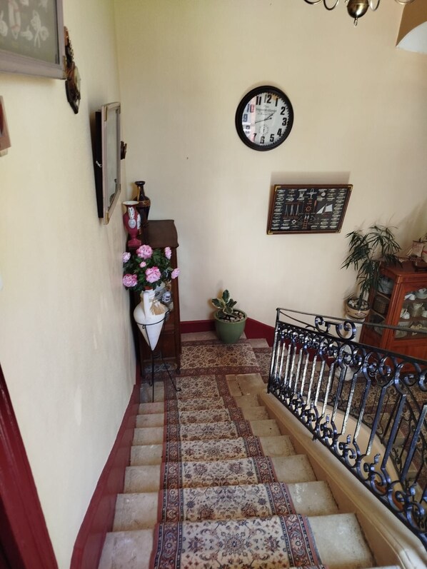 A staircase with patterned carpet, a clock, and a framed nautical chart on the wall.
