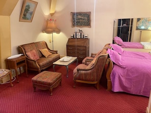 A room with a sofa, armchair, ottoman, a small table, a dresser, and a bed with pink bedding. - 18TH-CENTURY CLAIREFONTAINE GARCHIZY CASTLE (Garchizy)