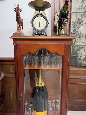 A wooden table with a glass shelf holding a champagne bottle and glasses. - 18TH-CENTURY CLAIREFONTAINE GARCHIZY CASTLE (Garchizy)