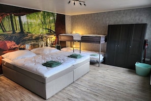 A bedroom with a large bed, a bunk bed, a wardrobe, and a forest-themed mural on the wall. - Kriemhild's Dragon's Cave (Xanten)