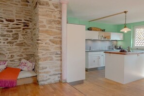 A kitchen with white cabinets, a wooden island, and a stone wall. - House of the Painter Cloud One (Müllheim)