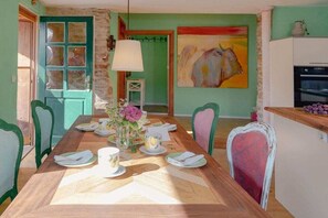 A dining area with a wooden table set for four, chairs, a vase with flowers, and a painting on the wall. - House of the Painter Cloud One (Müllheim)