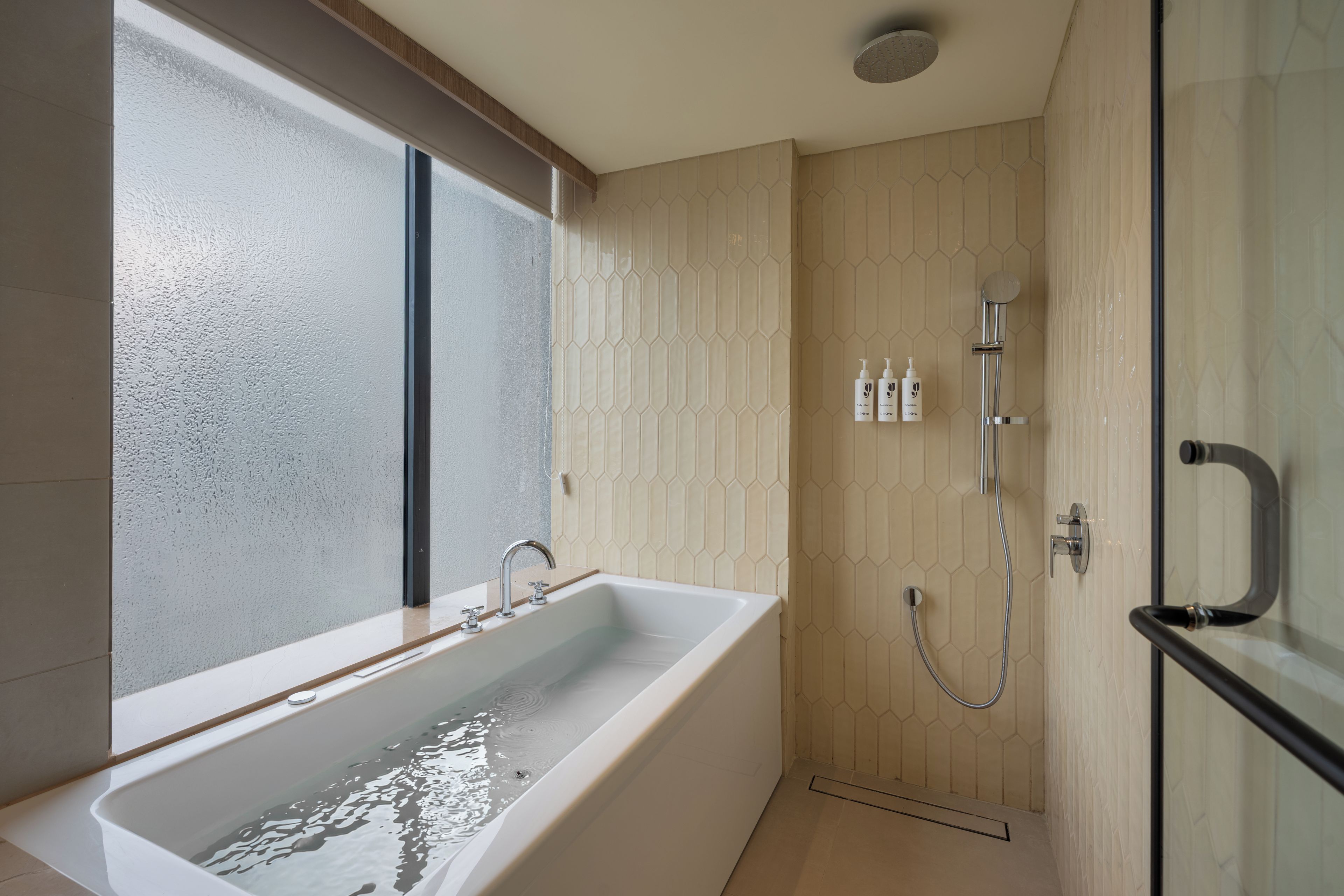 A modern bathroom with a bathtub, shower, and a window.
