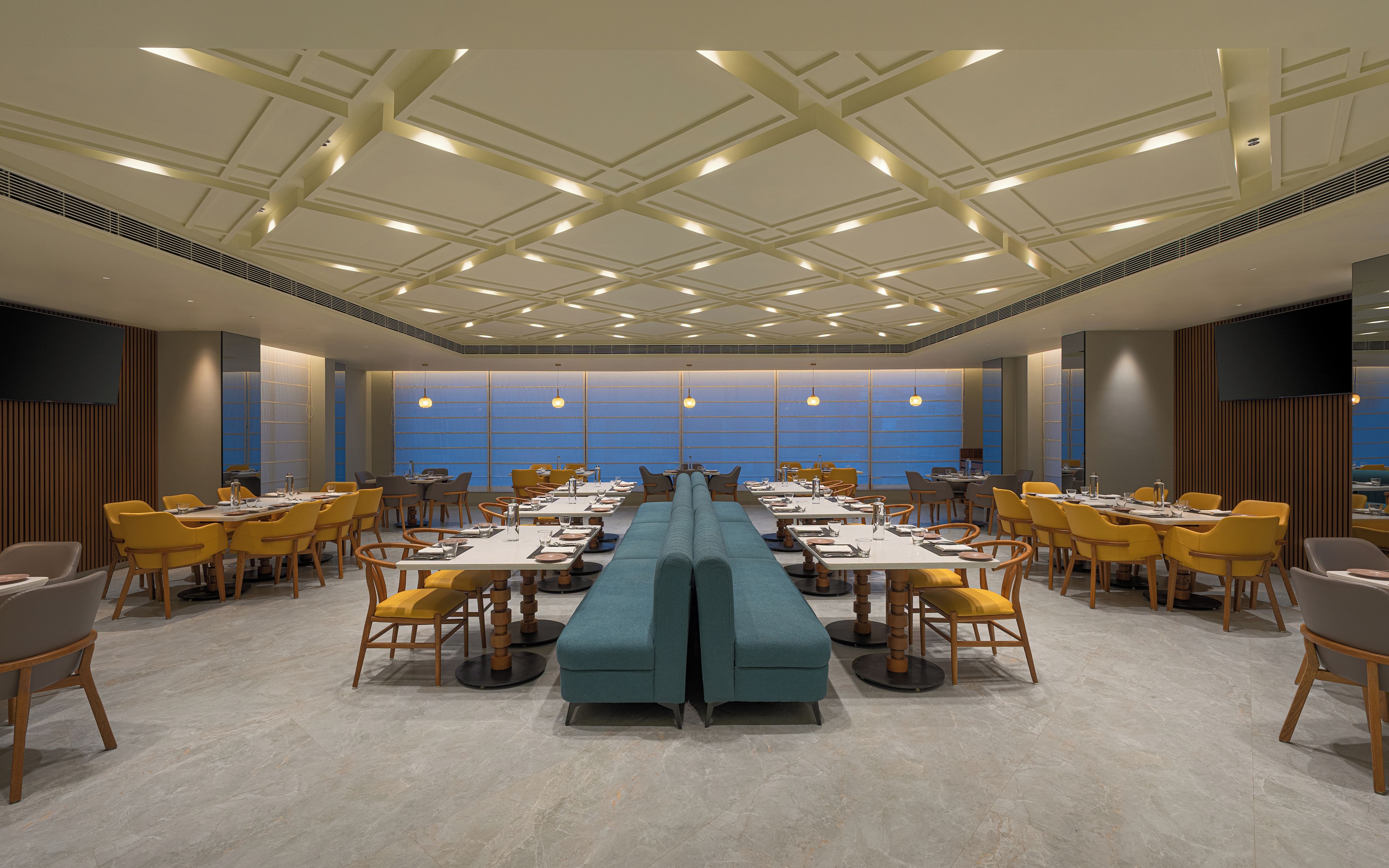 A conference room with a long table, yellow chairs, and a blue sofa.