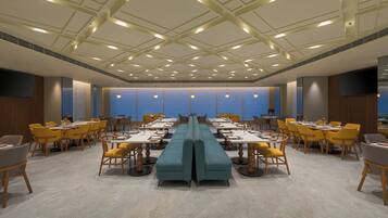 A conference room with a long table, yellow chairs, and a blue sofa.