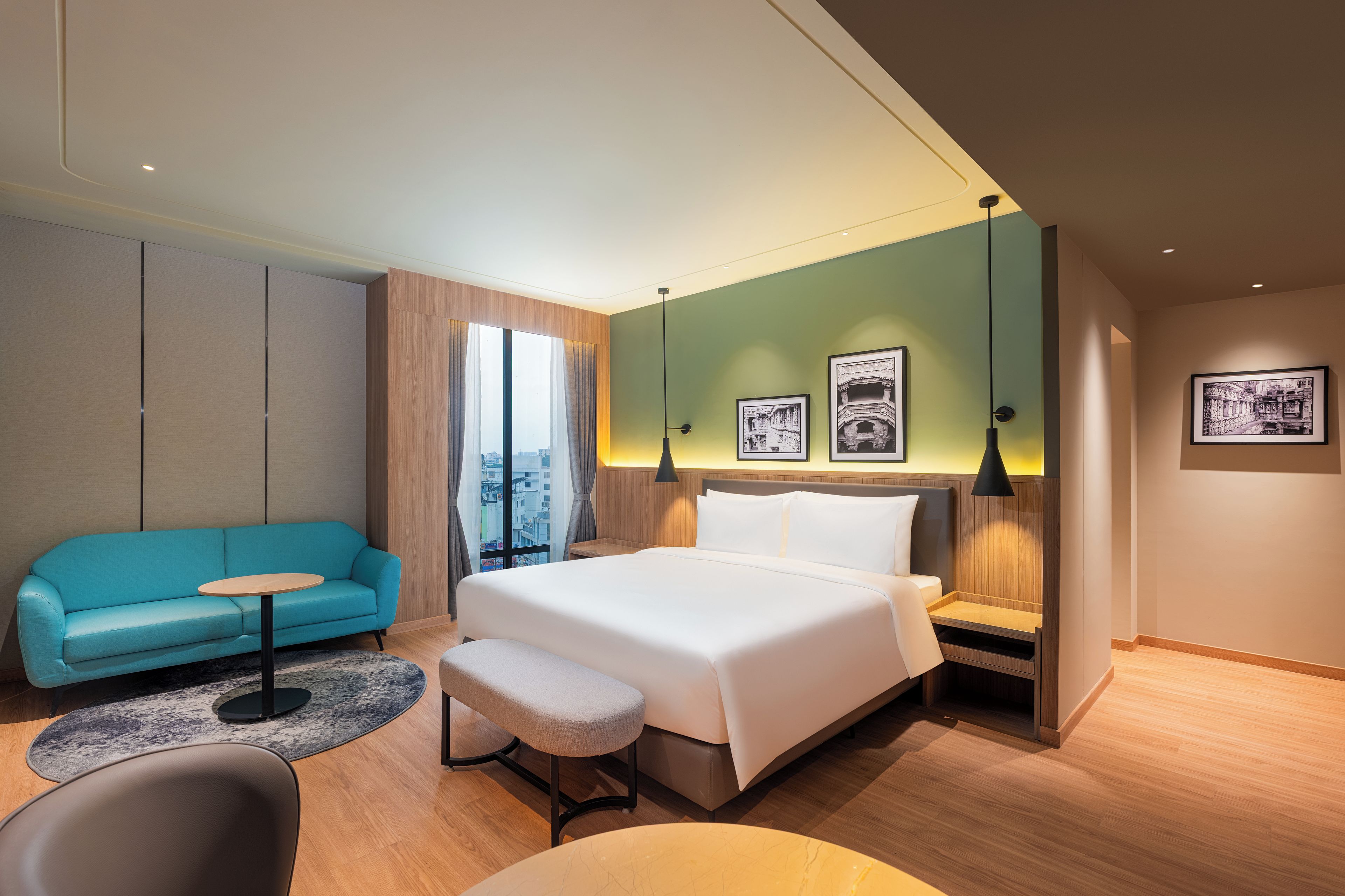 A modern hotel room with a bed, a sofa, a small table, and a chair.
