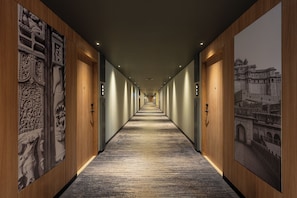 A long corridor with wooden doors and walls, featuring detailed carvings and a carpeted floor. - Park Inn & Suites By Radisson Rajkot (Rajkot)