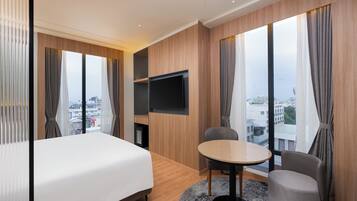 Habitación de hotel con cama, televisión, mesa de comedor y vistas a la ciudad.
