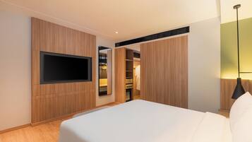 A hotel room with a bed, a TV mounted on the wall, a wardrobe, and a mirror.