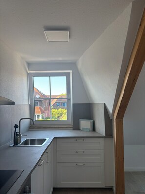 A small kitchen with a window, a sink, and cabinets. - Inselruhe - Ihre Auszeit auf Fehmarn (Fehmarn)