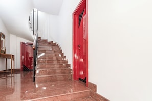 A staircase with a handrail leading to a red door. - Holiday Home (Matino)