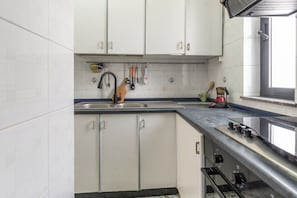 A kitchen with white cabinets, a stainless steel sink, and a coffee maker on the counter. - Holiday Home (Matino)