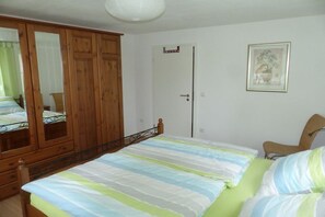 A bedroom with a bed, a wardrobe, a door, and a framed picture on the wall. - Holiday apartment with 2 bedrooms (Mühlhausen-Ehingen)