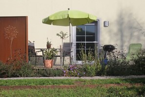A patio area with a green umbrella, a wooden door, and a window. - Holiday apartment with 2 bedrooms (Mühlhausen-Ehingen)