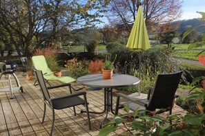 An outdoor patio with a round table and chairs, surrounded by potted plants and a view of a landscape. - Holiday apartment with 2 bedrooms (Mühlhausen-Ehingen)