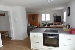 A modern kitchen with a built-in oven, a sink, and a dining area with a table and chairs. - Holiday apartment with 2 bedrooms (Mühlhausen-Ehingen)