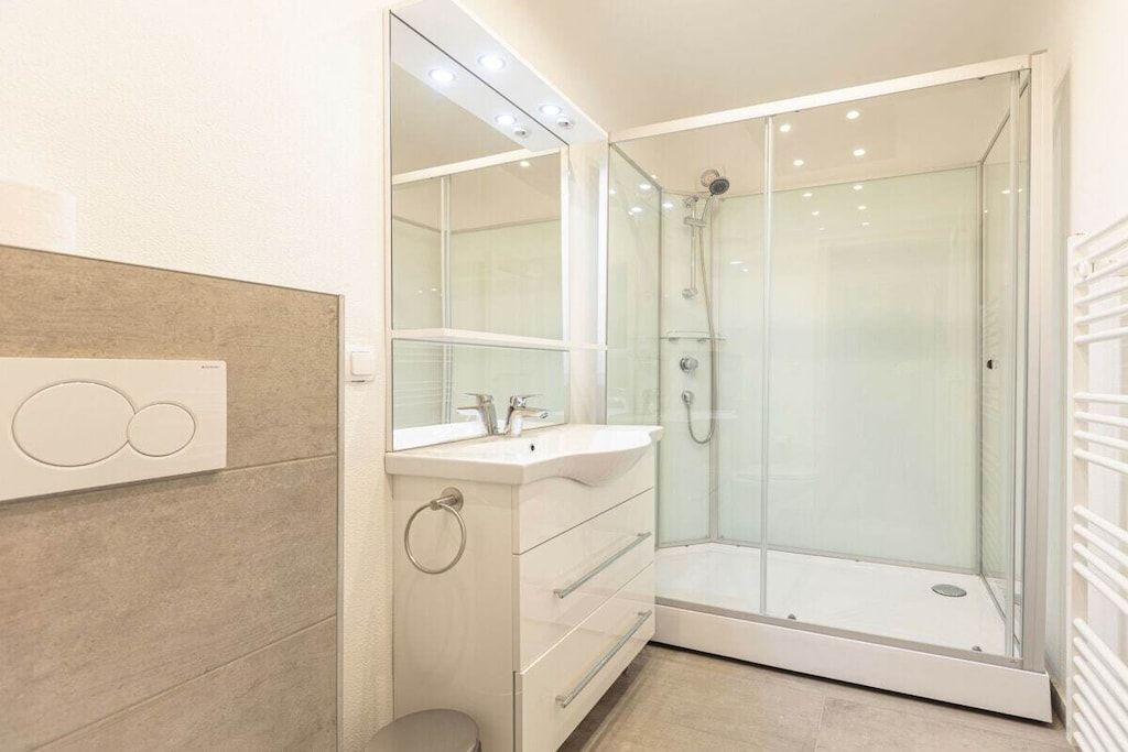 A modern bathroom with a glass-enclosed shower, a vanity with a mirror, and a toilet.
