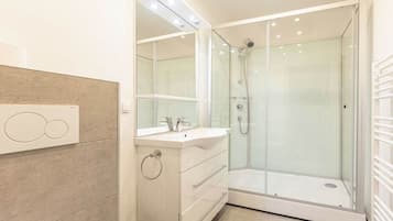 A modern bathroom with a glass-enclosed shower, a vanity with a mirror, and a toilet.