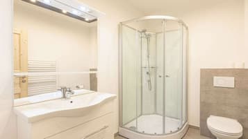 Ein modernes Badezimmer mit einer Duschkabine, einem weißen Waschbecken und einer Toilette.