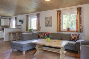 Un salon chaleureux avec un canapé, une table basse et un coin repas agrémenté d’un tabouret de bar.
