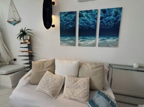 A bedroom with a bed, pillows, a wall-mounted shelf, a potted plant, and a wall art piece depicting an underwater scene. - views and big terrace  steps from the beach (Baja Sardinia)