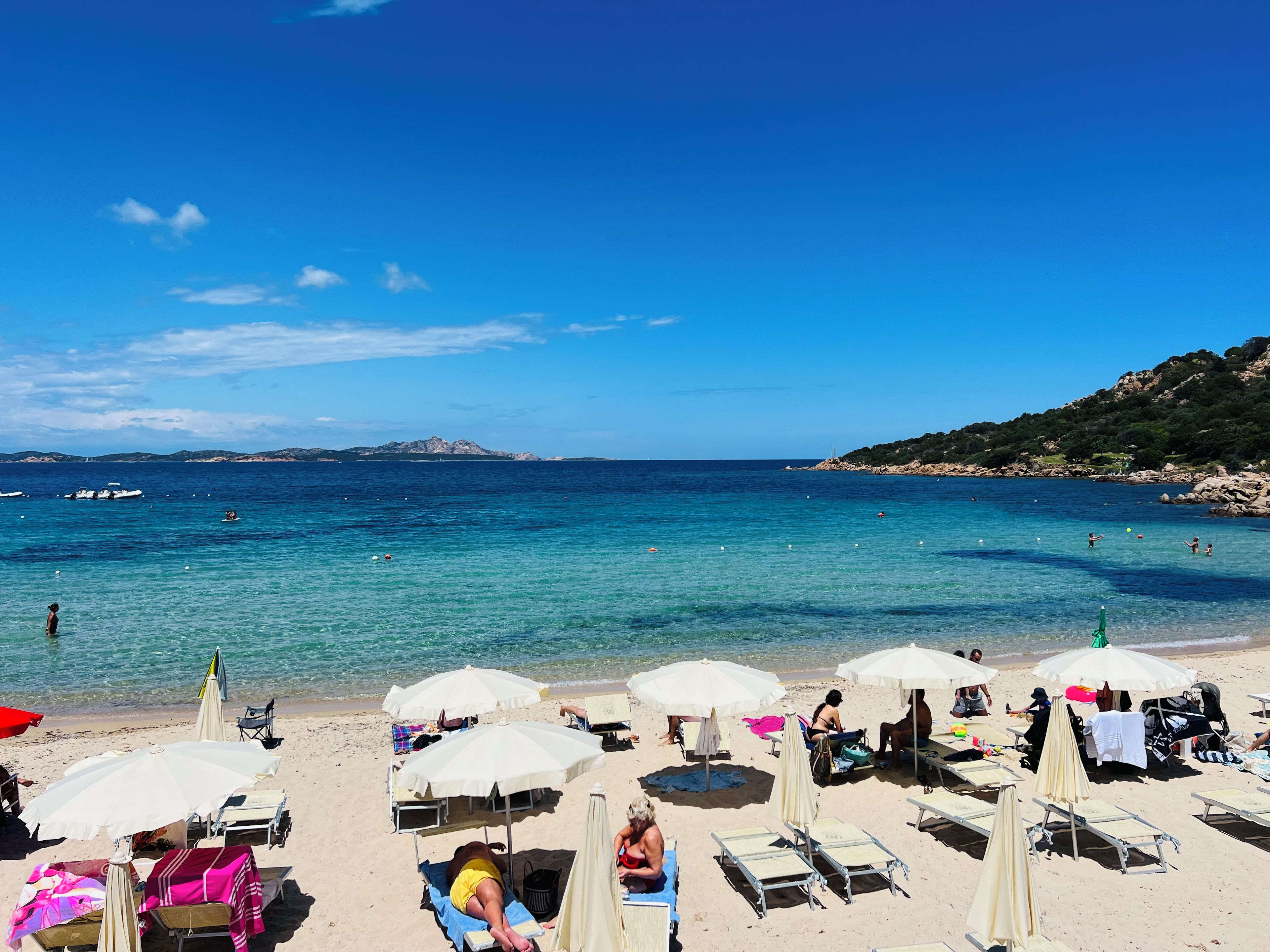 A beach with sun loungers, umbrellas, and a clear view of the sea.