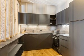 A modern kitchen with dark cabinetry, a wooden countertop, and a built-in oven. - Apartment in Fügen with swimming pool (Fügen)