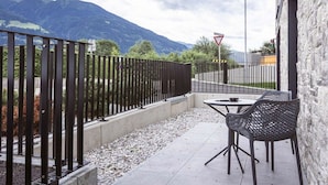 Un pati amb una taula i cadires, una tanca de metall i vista a la muntanya.