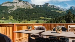A wooden deck with a table and chairs, overlooking a mountainous landscape. - Cabin in Annaberg with swimming pool (Annaberg)