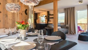 A dining area with a table set for four, a vase with flowers, and a view of the outdoors. - Cabin in Annaberg with swimming pool (Annaberg)