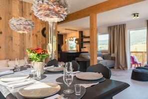 A dining area with a table set for four, a vase with flowers, and a view of the outdoors. - Cabin in Annaberg with swimming pool (Annaberg)