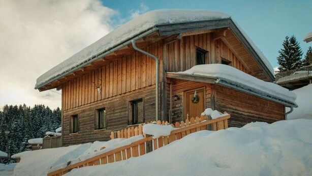 A wooden cabin with a snow-covered roof and a wooden fence. - Cabin in Annaberg with swimming pool (Annaberg)