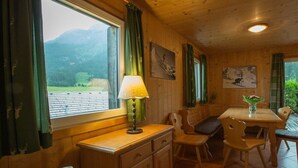 A wooden interior with a dining table, chairs, a lamp, and artwork on the walls. - Cabin in Annaberg with swimming pool (Annaberg)
