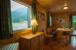 A wooden interior with a dining table, chairs, a lamp, and artwork on the walls. - Cabin in Annaberg with swimming pool (Annaberg)