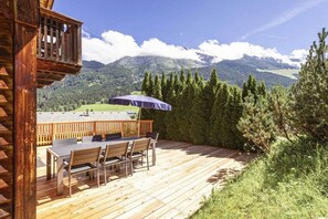 A wooden deck with a table and chairs, overlooking a mountainous landscape. - Cabin in Annaberg with swimming pool (Annaberg)