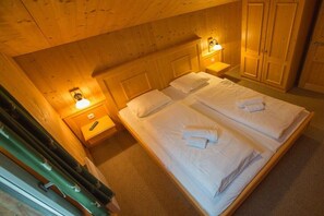 A room with two beds, wooden walls, a wardrobe, and bedside lamps. - Cabin in Annaberg with swimming pool (Annaberg)