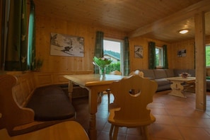 A wooden interior with a dining table, chairs, a sofa, and artwork on the walls. - Cabin in Annaberg with swimming pool (Annaberg)