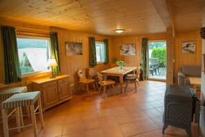 A wooden interior with a dining table, chairs, a bench, and a stove. - Cabin in Annaberg with swimming pool (Annaberg)