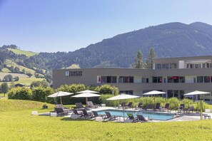 A hotel with a swimming pool, lounge chairs, and umbrellas. - Apartment in Radstadt with swimming pool (Radstadt)