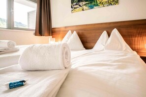 A hotel room with a neatly made bed, a rolled white towel, and a small blue object on the bed. - Apartment in Radstadt with swimming pool (Radstadt)