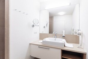 A modern bathroom with a white sink, a mirror, and a hairdryer on the countertop. - Apartment in Radstadt with swimming pool (Radstadt)
